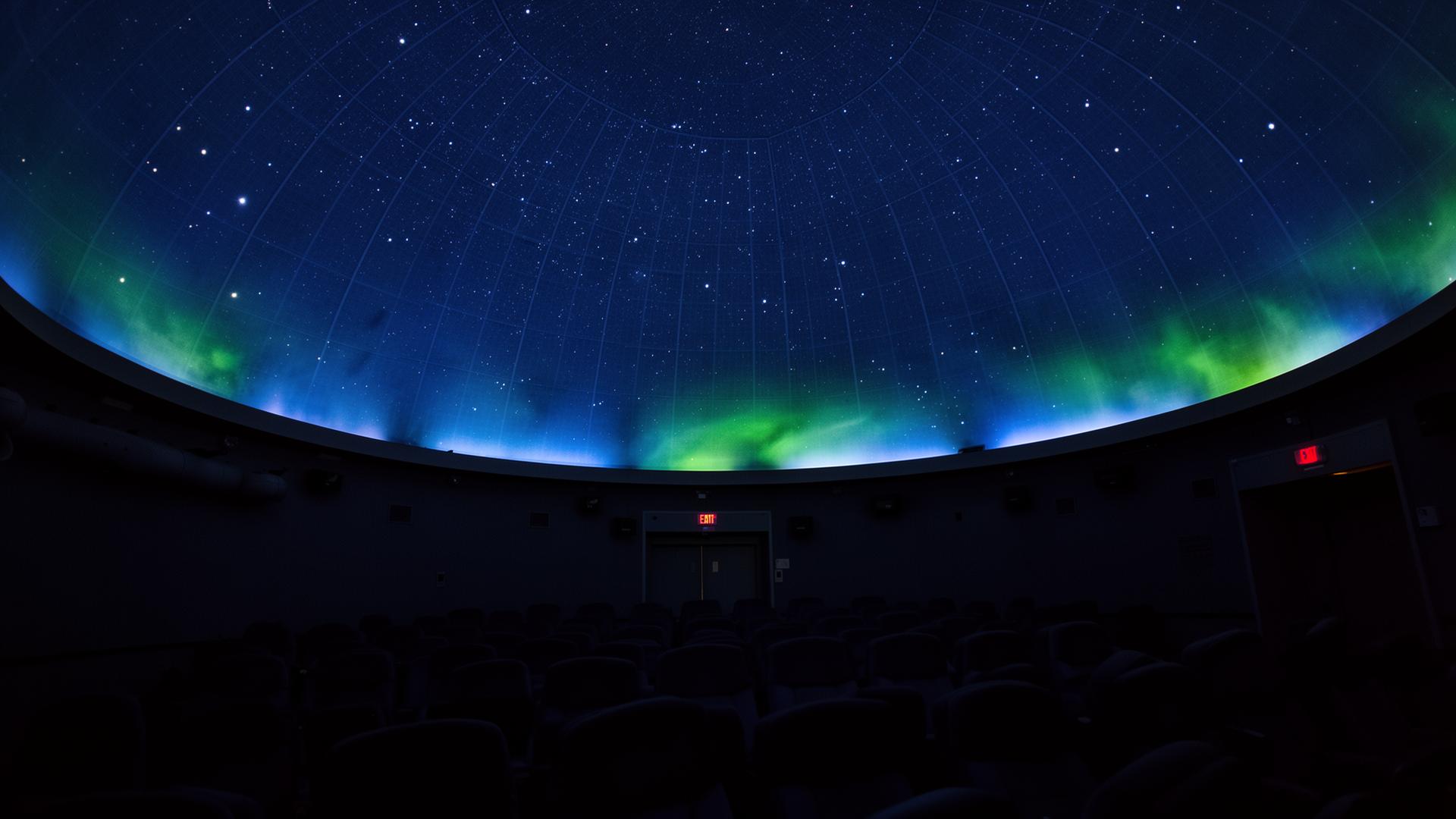 Interior of a planetarium dome with a starfield and green aurora projection